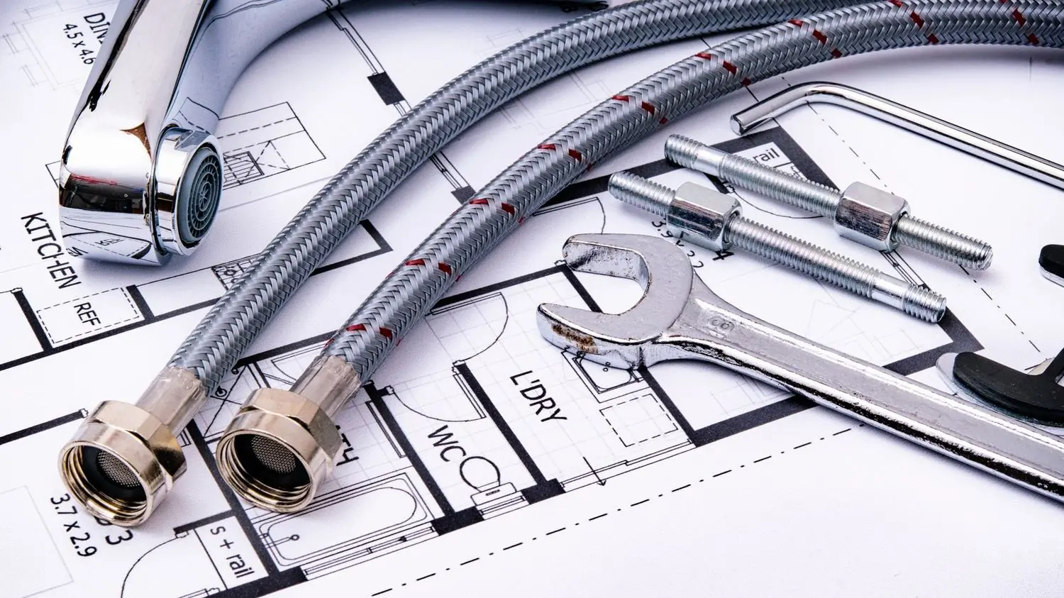 Braided supply hoses and wrenches laid on a plumbing plan