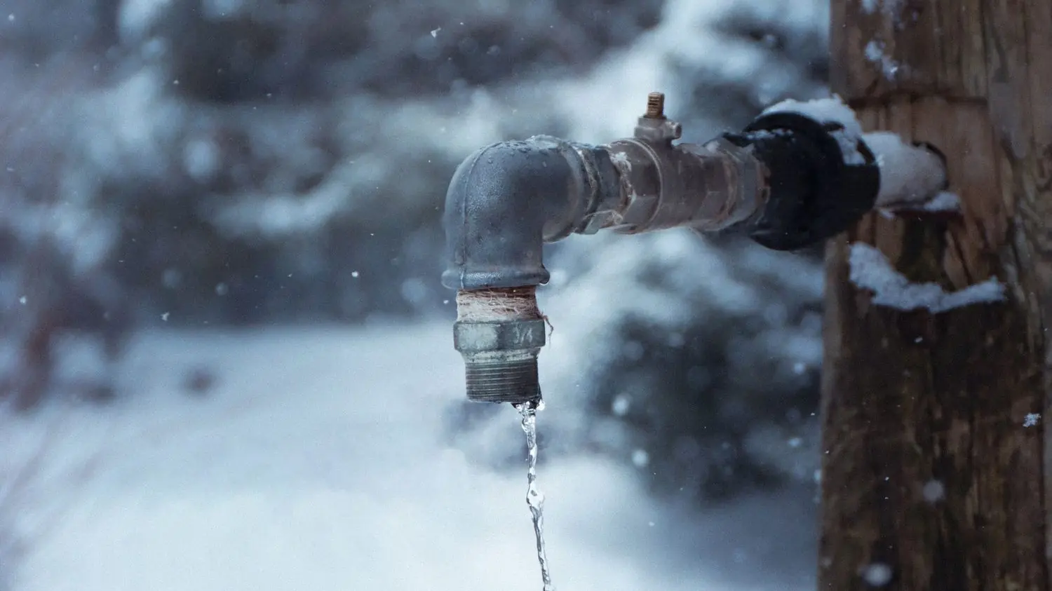 Frozen outdoor spigot dripping in the snow