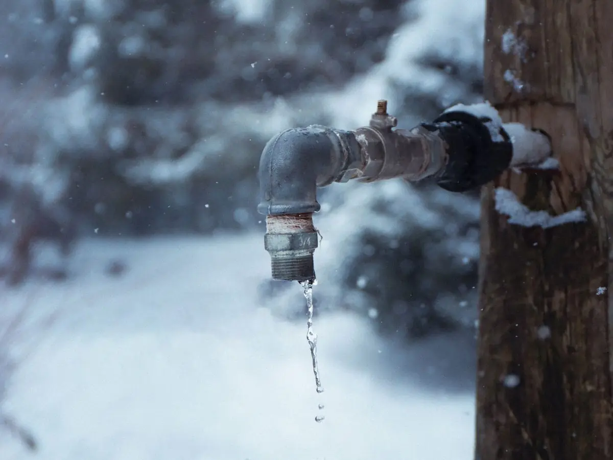 Frozen outdoor spigot dripping in the snow