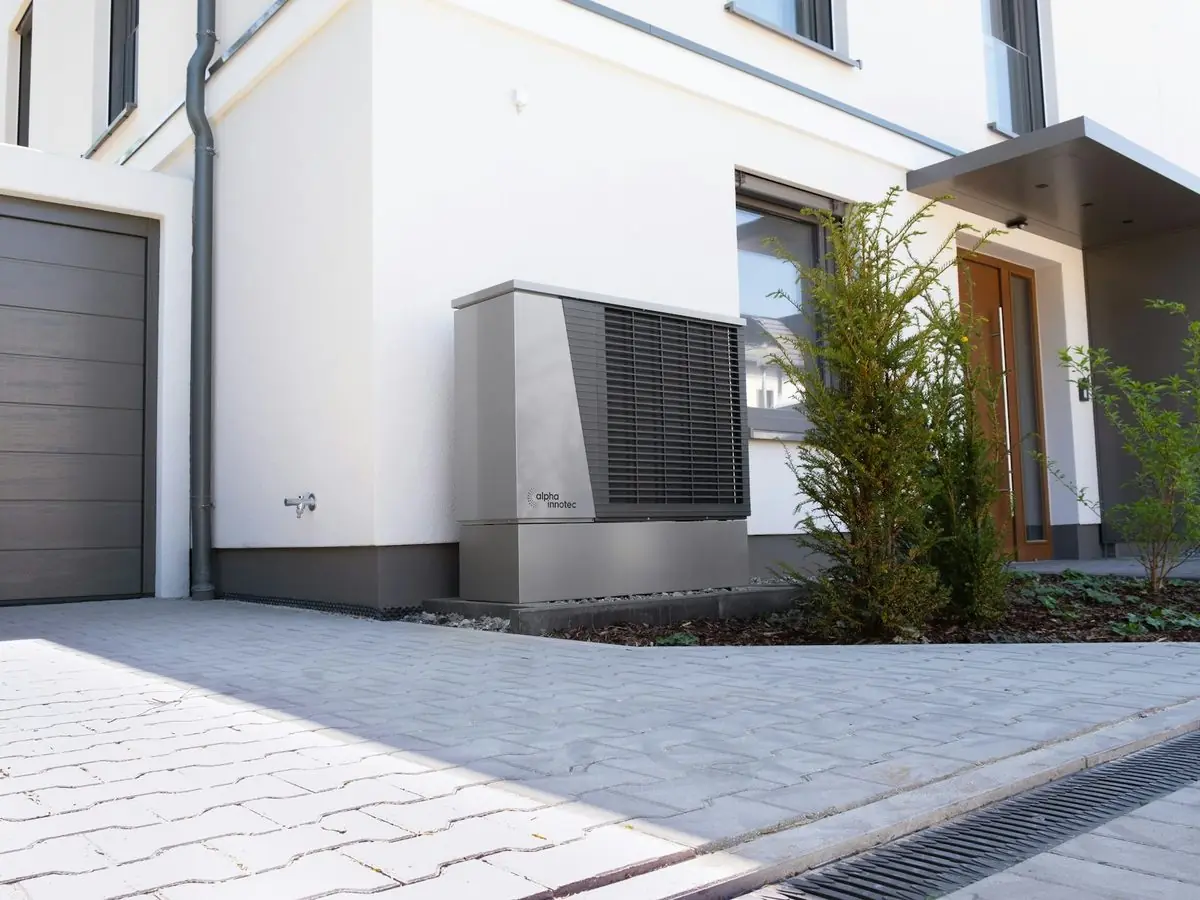 Heat pump unit beside a newer house