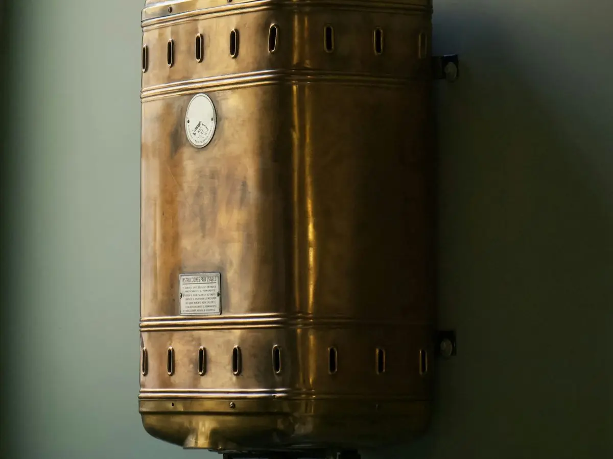 Old brass-colored water heater tank against a wall