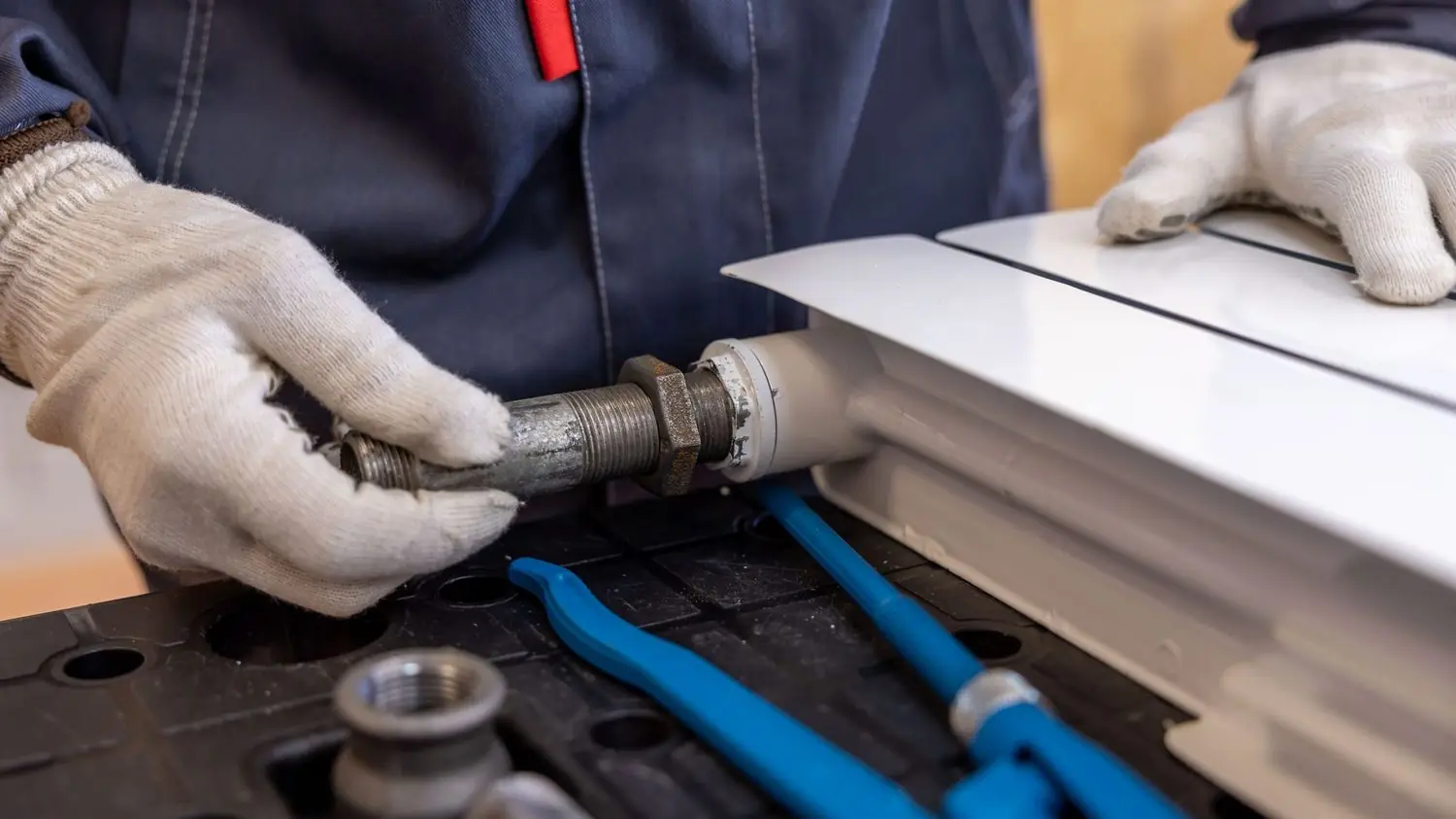 Plumber in gloves fitting a pipe joint