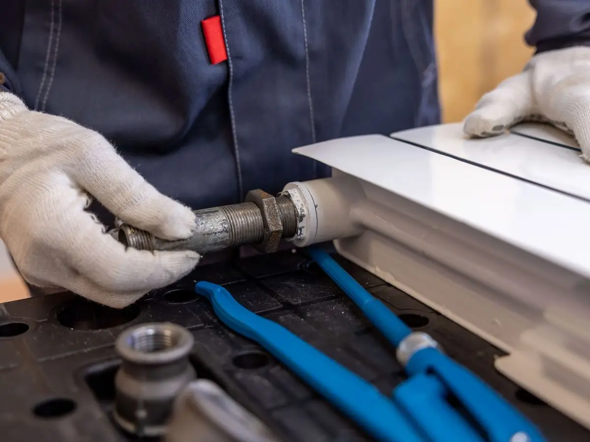 Plumber in gloves fitting a pipe joint