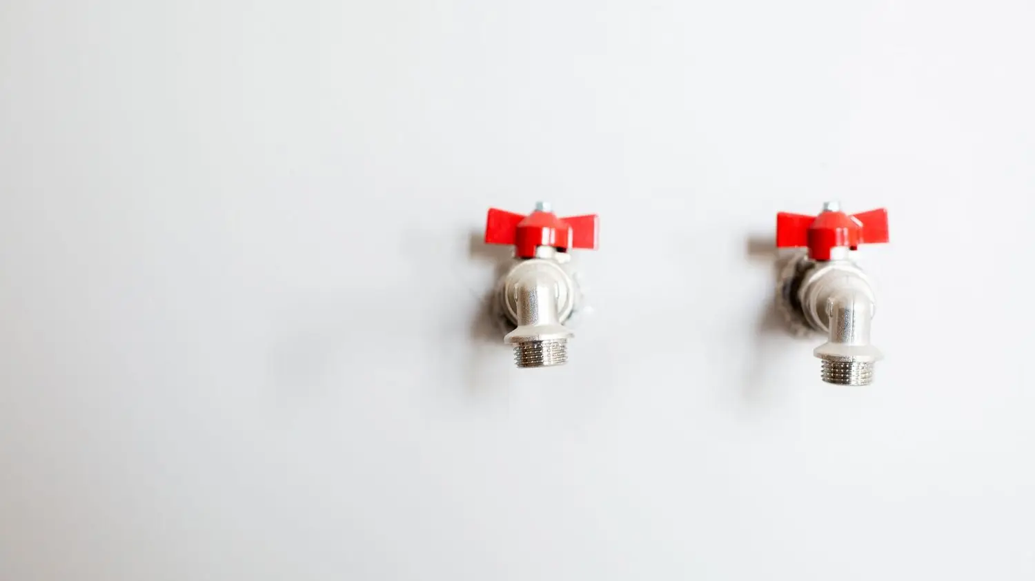 Hot and cold water shutoff valves on a wall