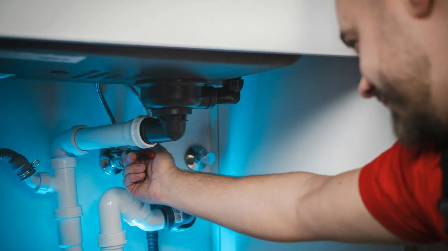 Plumber working on the water lines under a sink