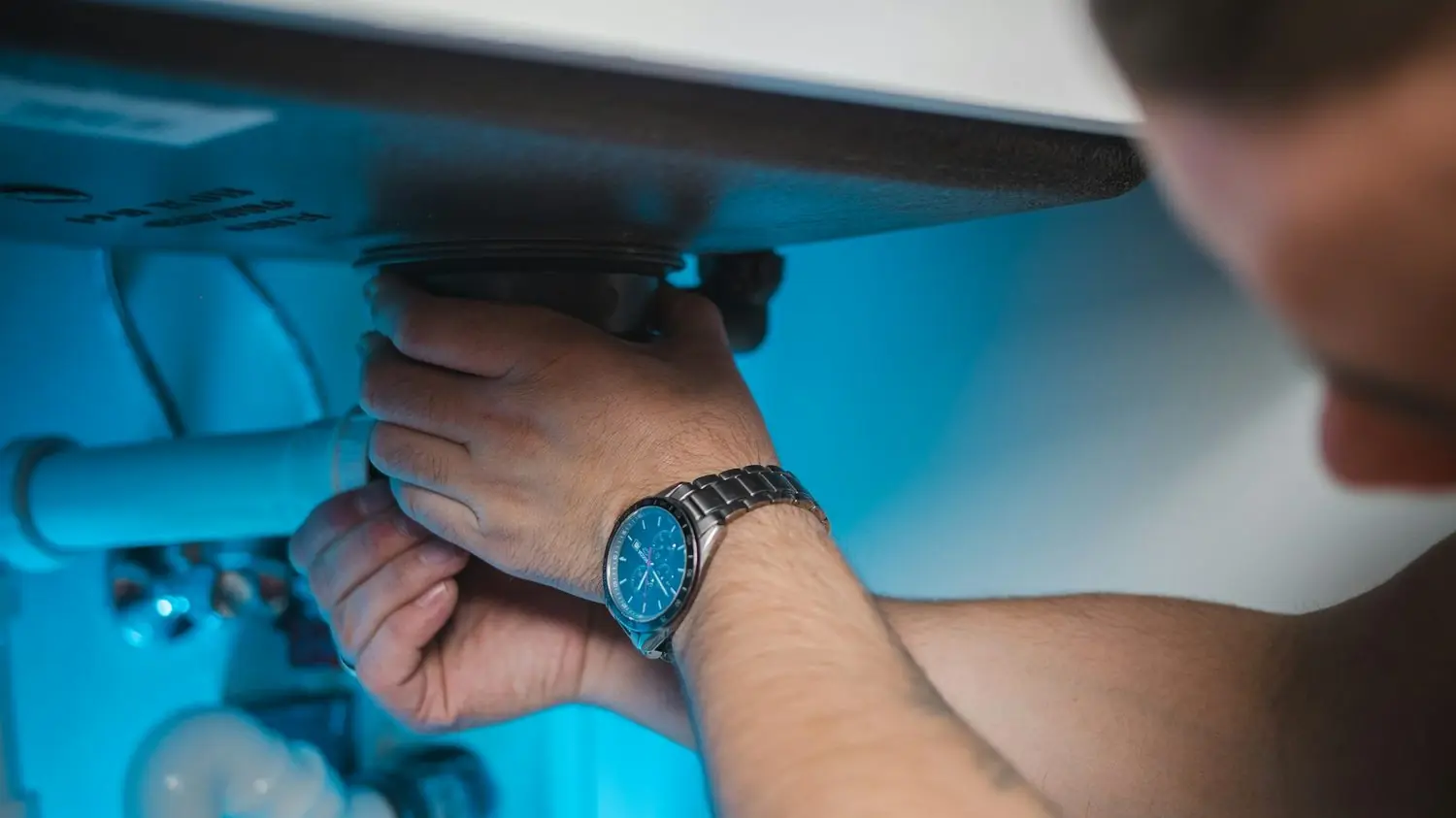Plumber connecting a supply line under a sink