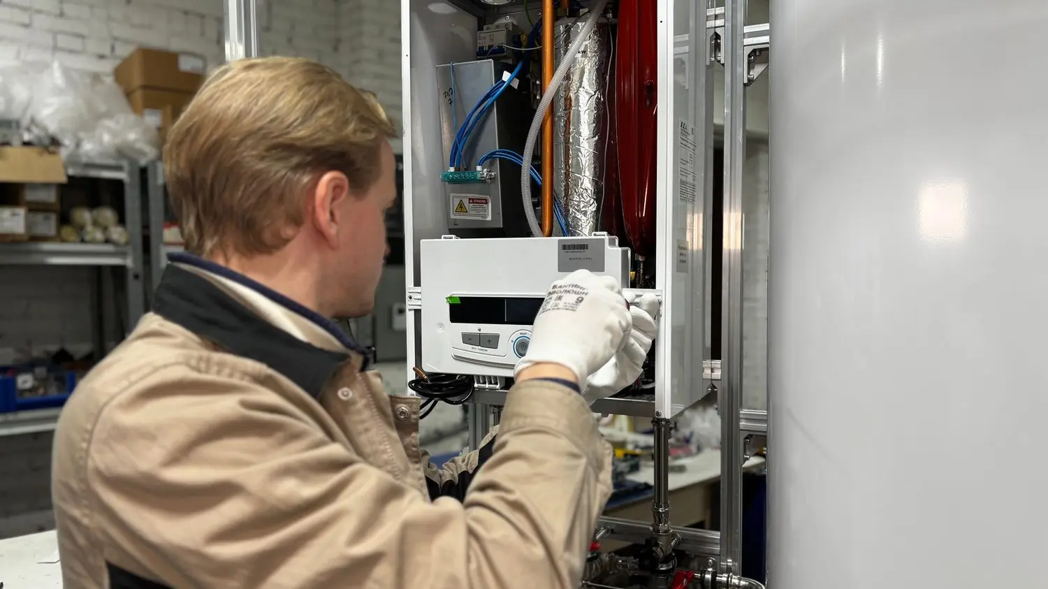 Technician in gloves servicing a wall-mounted heating unit