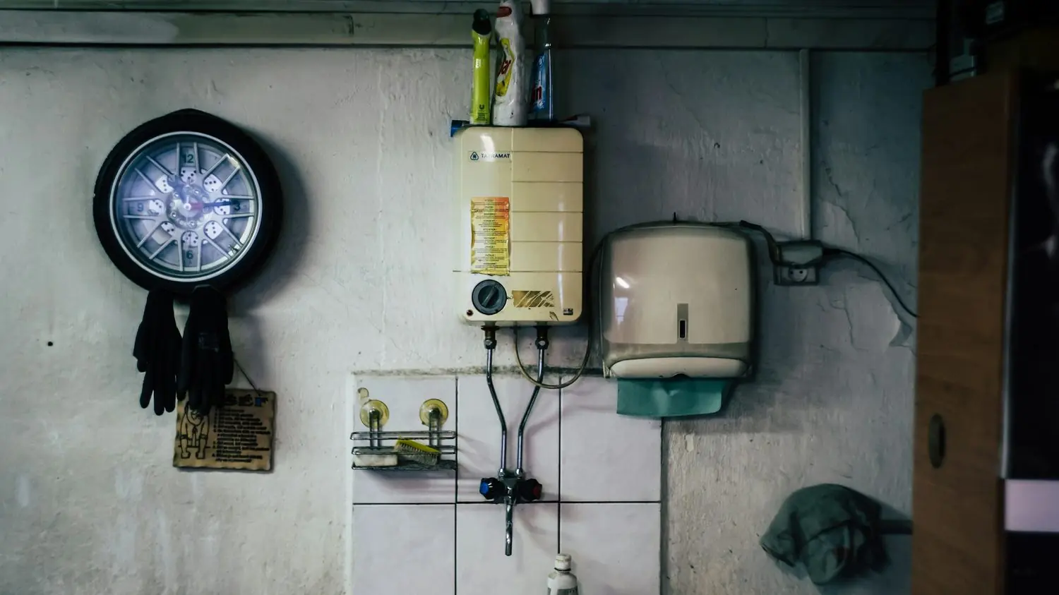 Small water heater mounted on a basement utility room wall